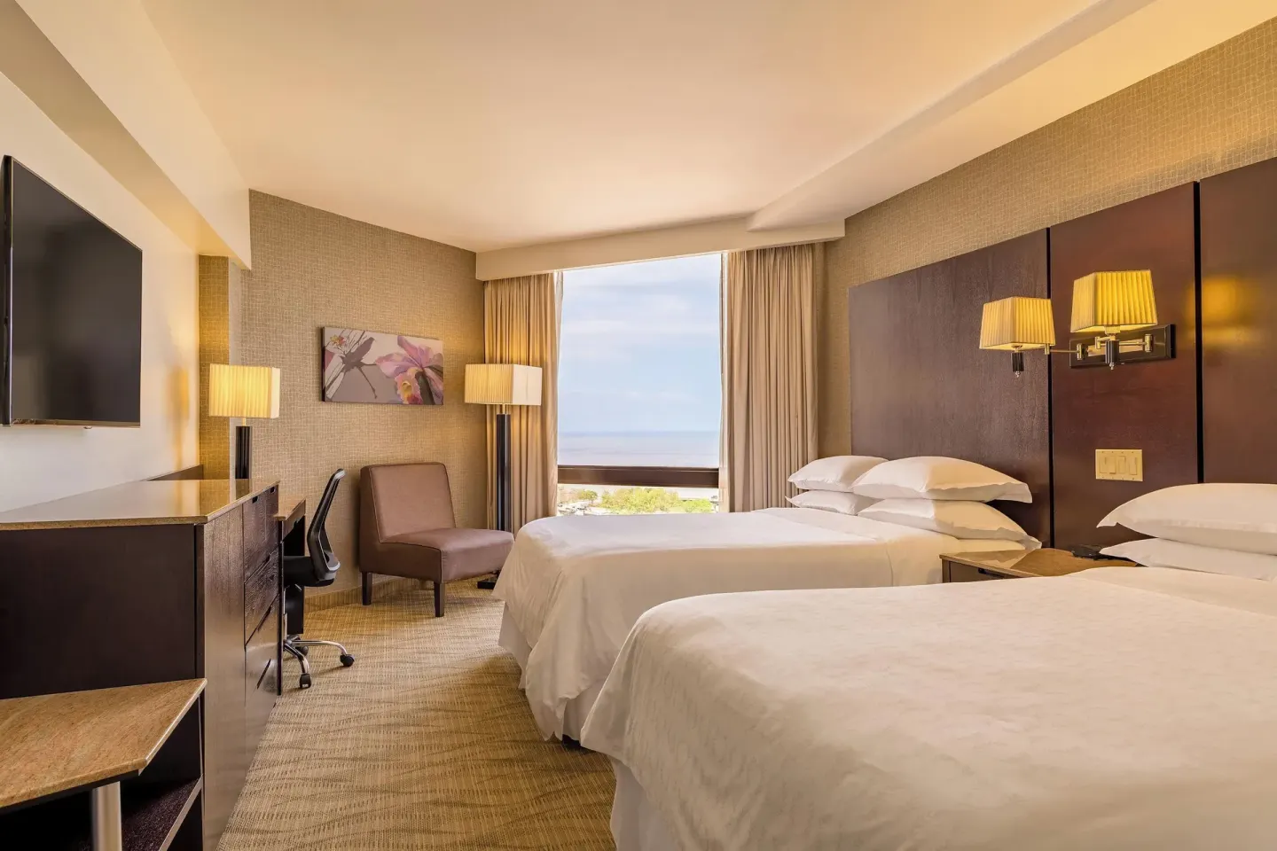 Deluxe Room with two beds, desk, TV and ocean-facing window at Sheraton Grand Panama.