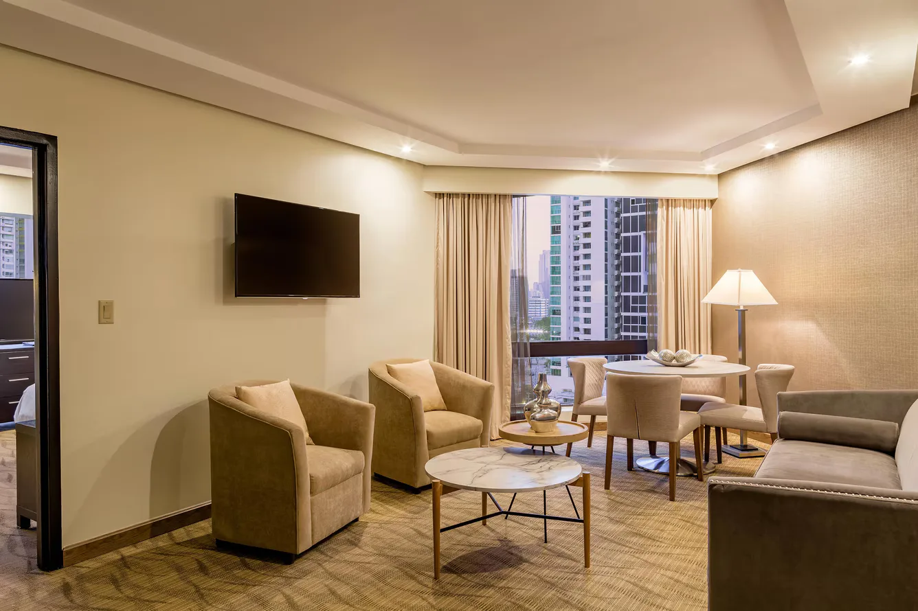 Deluxe room living and dining area with city window at Sheraton Grand Panama.