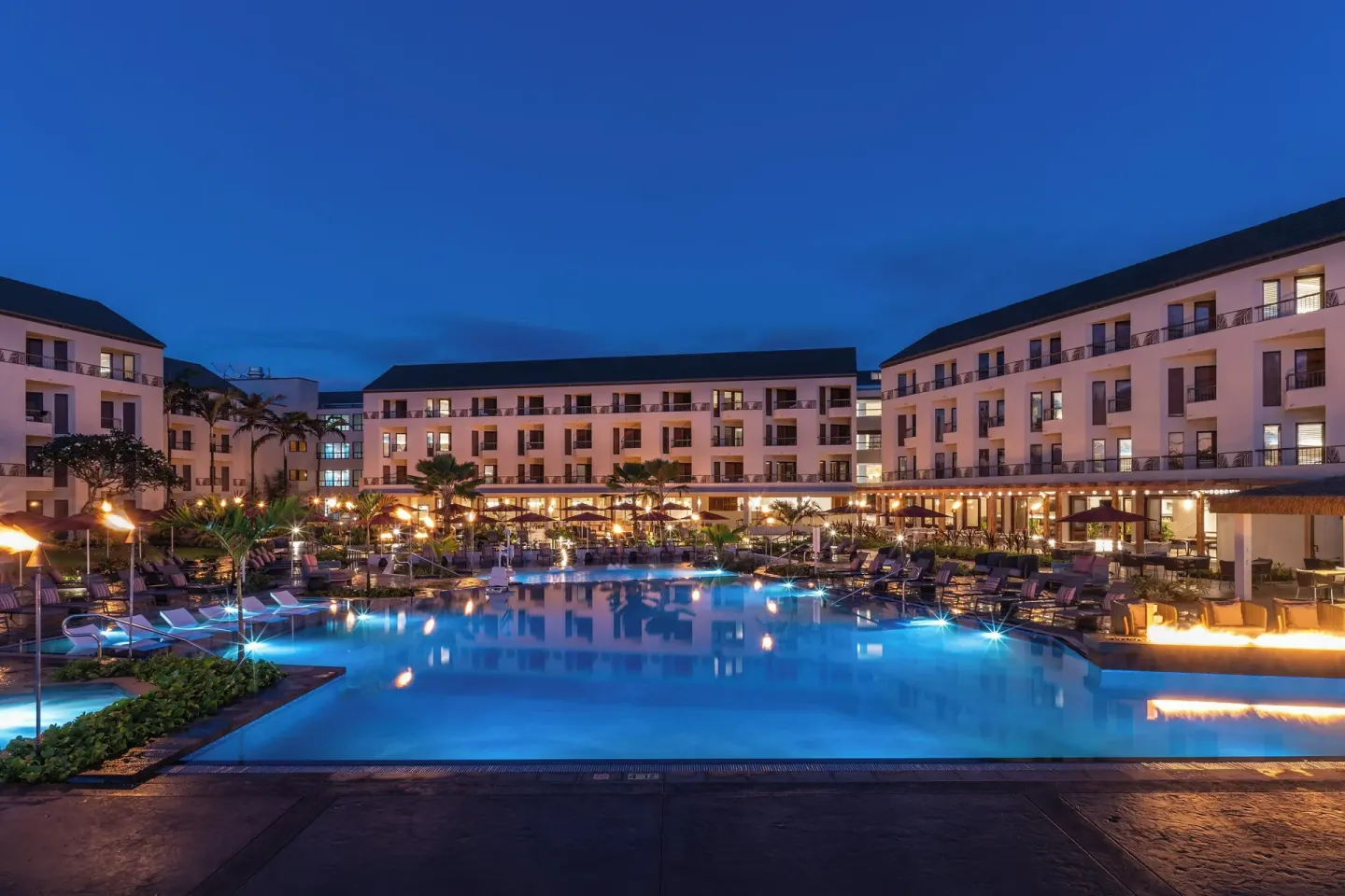 Blue-hour main pool at Sheraton Kauai Coconut Beach Resort with fire features and balconies.