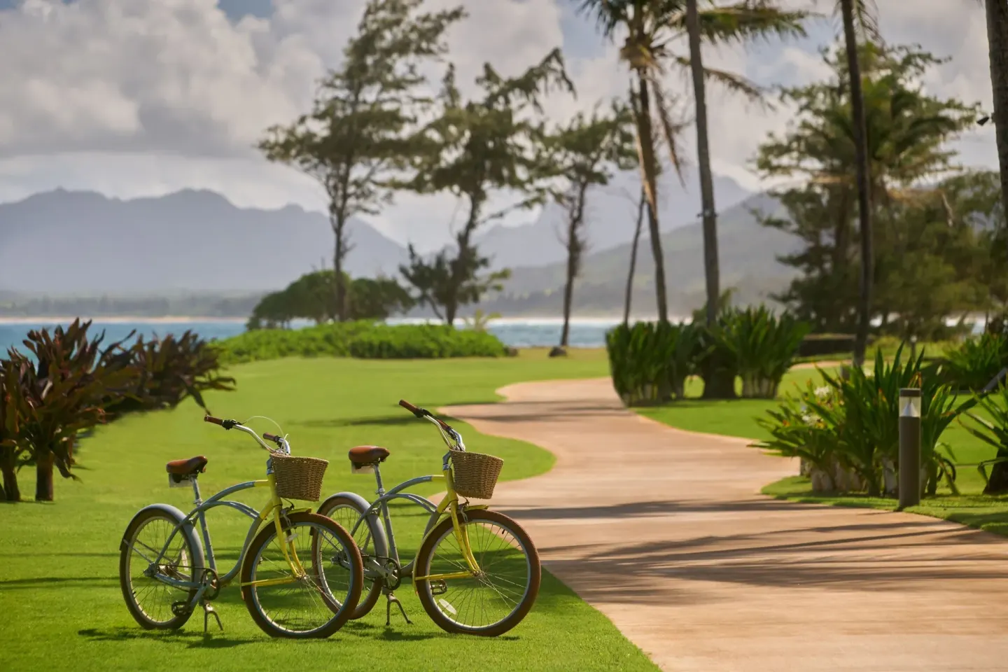 Two cruiser bicycles stand beside a landscaped path at Sheraton Kauai Coconut Beach Resort.