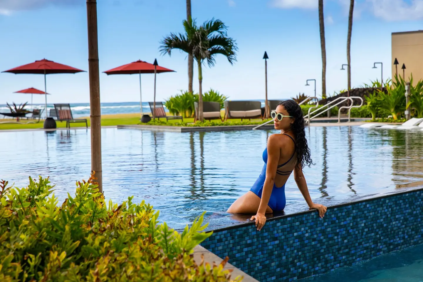 Guest sitting at the pool edge at Sheraton Kauai Coconut Beach Resort with ocean in view.