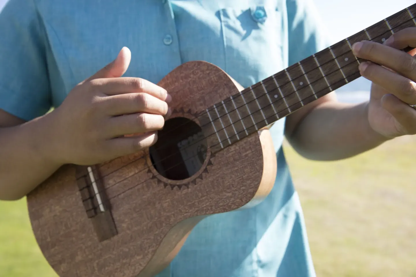 A person plays a ukulele outdoors at Sheraton Kauai Coconut Beach Resort.
