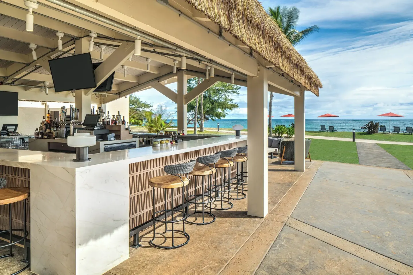 Beachfront open-air bar with ocean views at Sheraton Kauai Coconut Beach Resort.