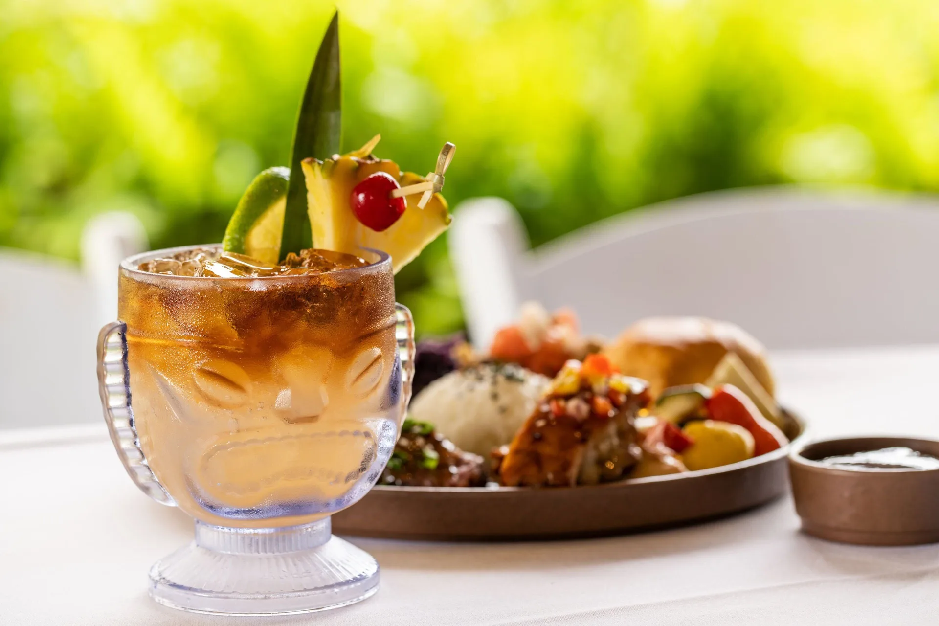 Tropical cocktail with a plated meal behind it at Sheraton Kauai Coconut Beach Resort.