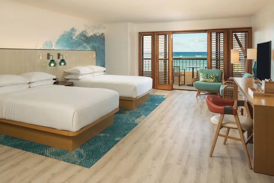 Two-bed guest room with ocean-facing balcony at Sheraton Kauai Coconut Beach Resort.