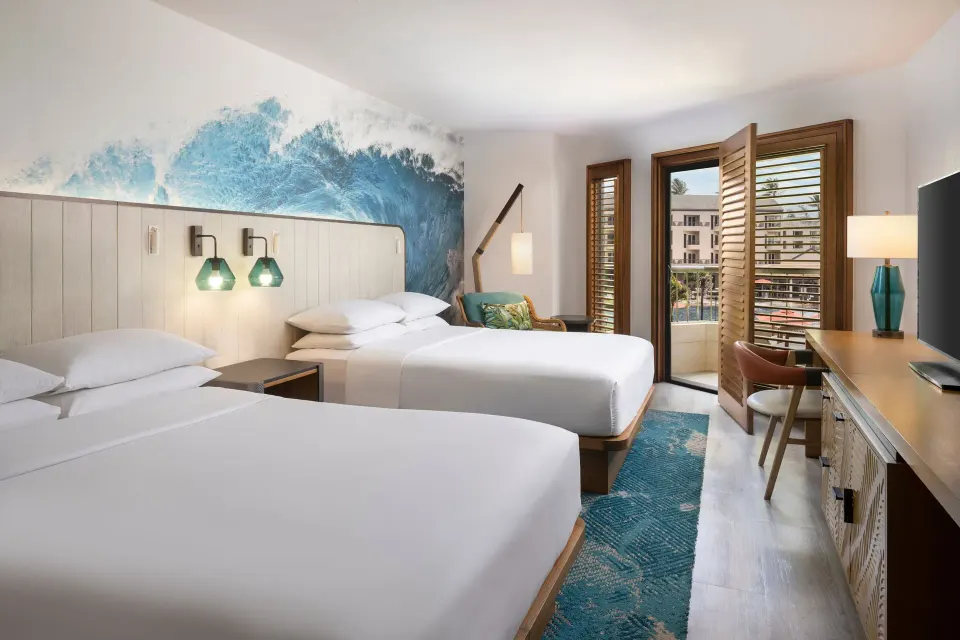 Two-bed guest room with desk and open shutters at Sheraton Kauai Coconut Beach Resort.