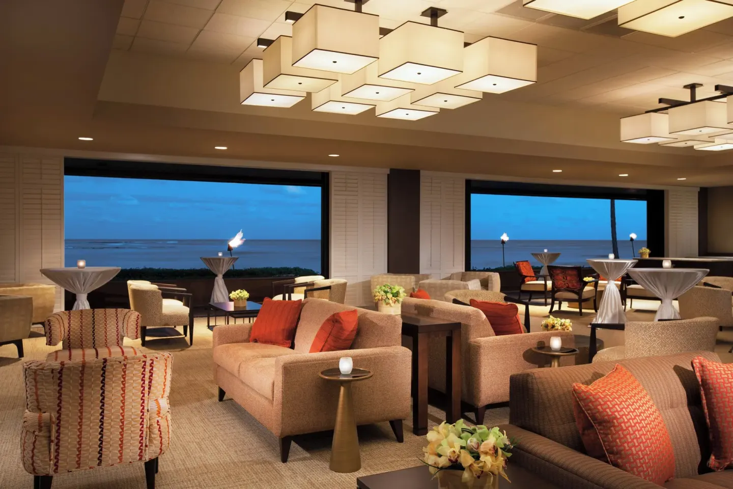 Lounge seating and cocktail tables facing ocean-view windows at Sheraton Kauai Resort.