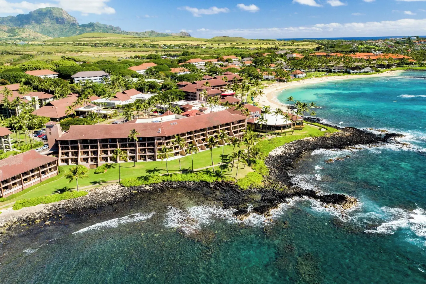 Aerial view of the oceanfront buildings, beach, and coastline at Sheraton Kauai Resort.