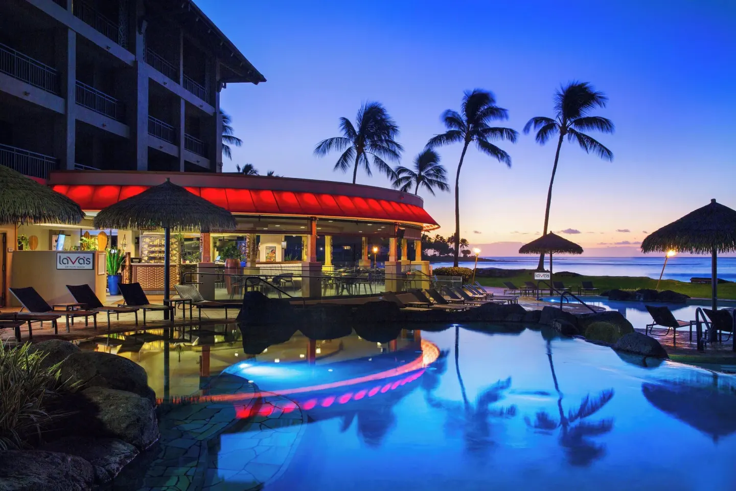 Poolside Lava's sign, restaurant, palm trees, and ocean at Sheraton Kauai Resort.