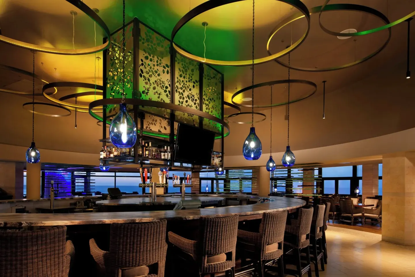 Curved bar with blue pendant lights inside RumFire at Sheraton Kauai Resort.