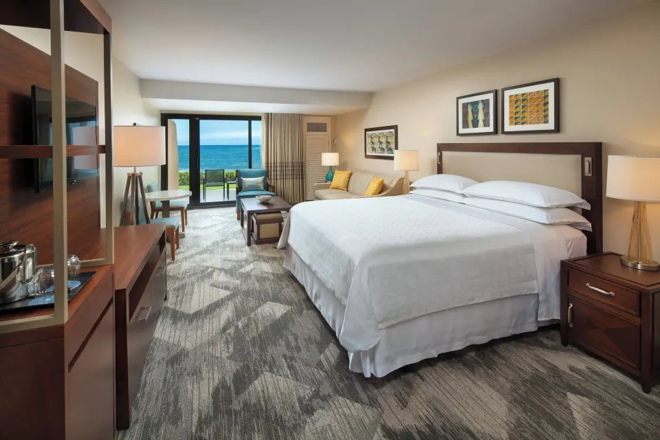 Deluxe Room Oceanfront king bed at Sheraton Kauai Resort with seating and ocean view.