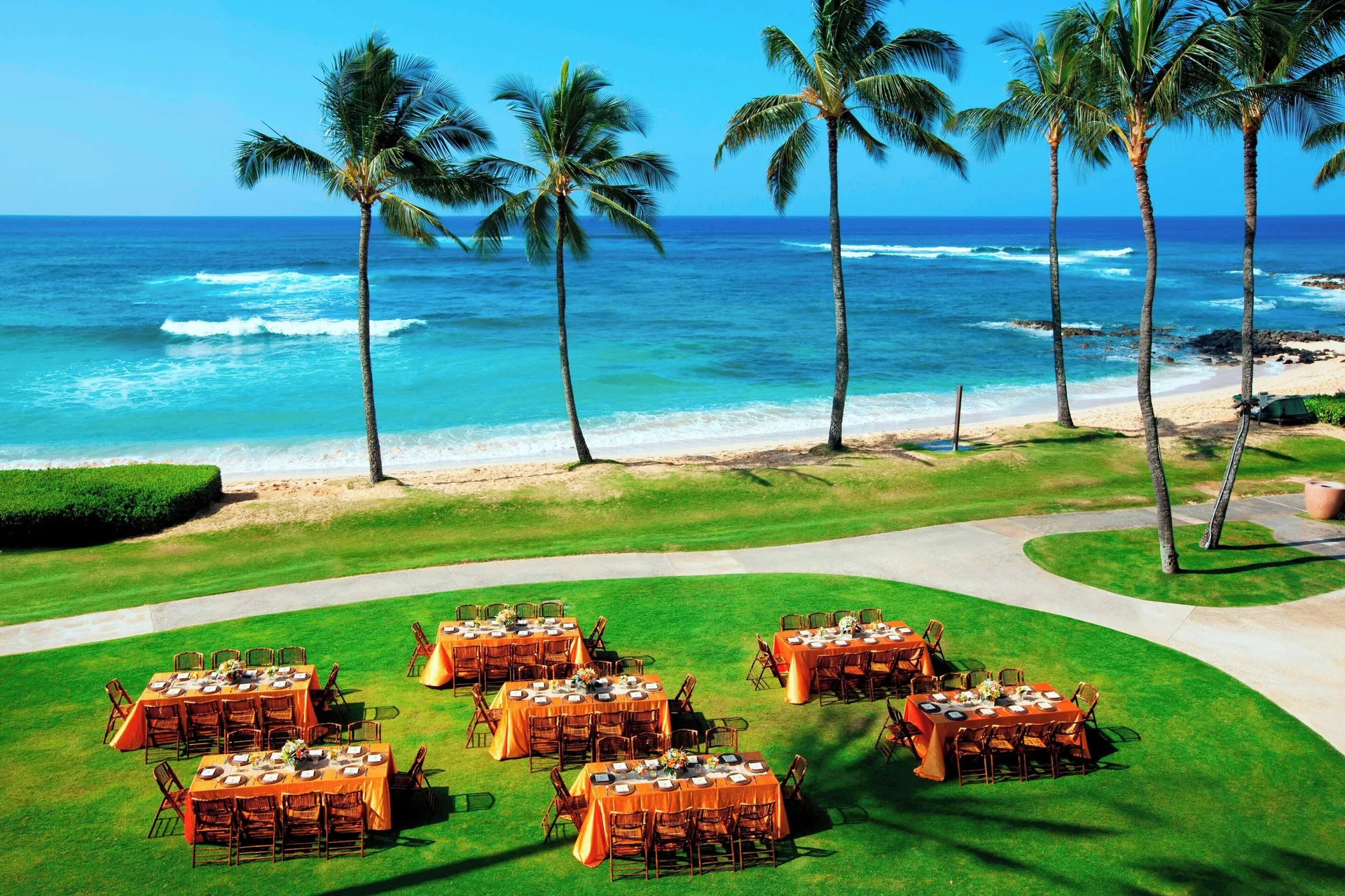 Oceanfront lawn set with banquet tables and palm trees at Sheraton Kauai Resort.