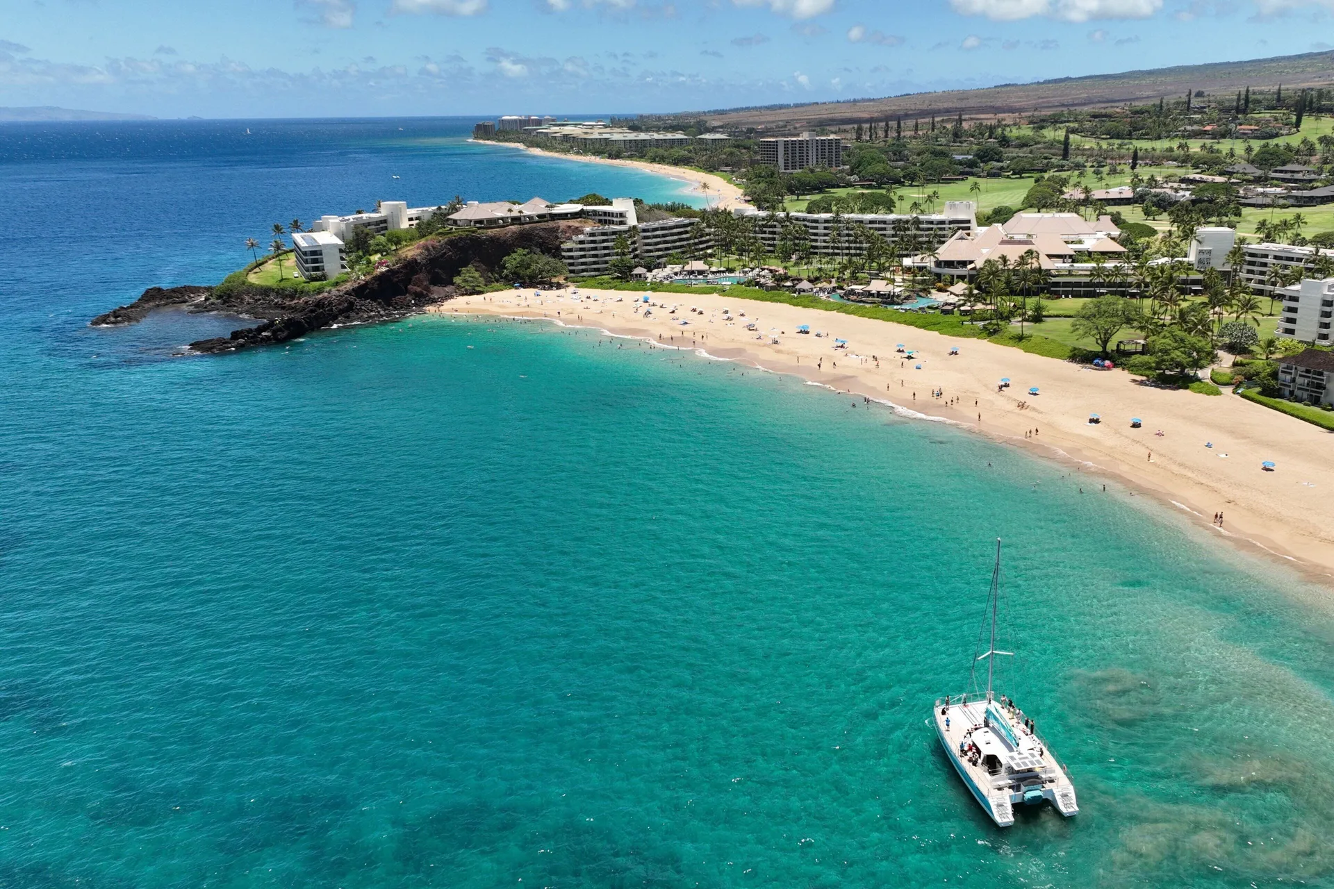 Aerial view of Sheraton Maui Resort & Spa, the beach, and a catamaran offshore.