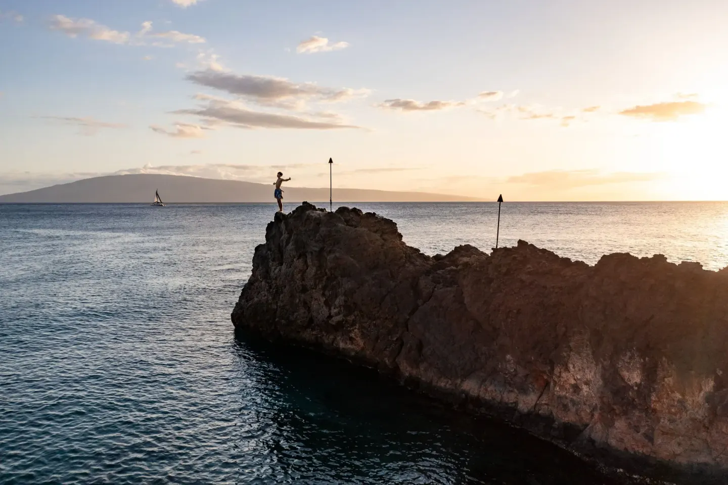A cliff diver stands on Black Rock at sunset near Sheraton Maui Resort & Spa.