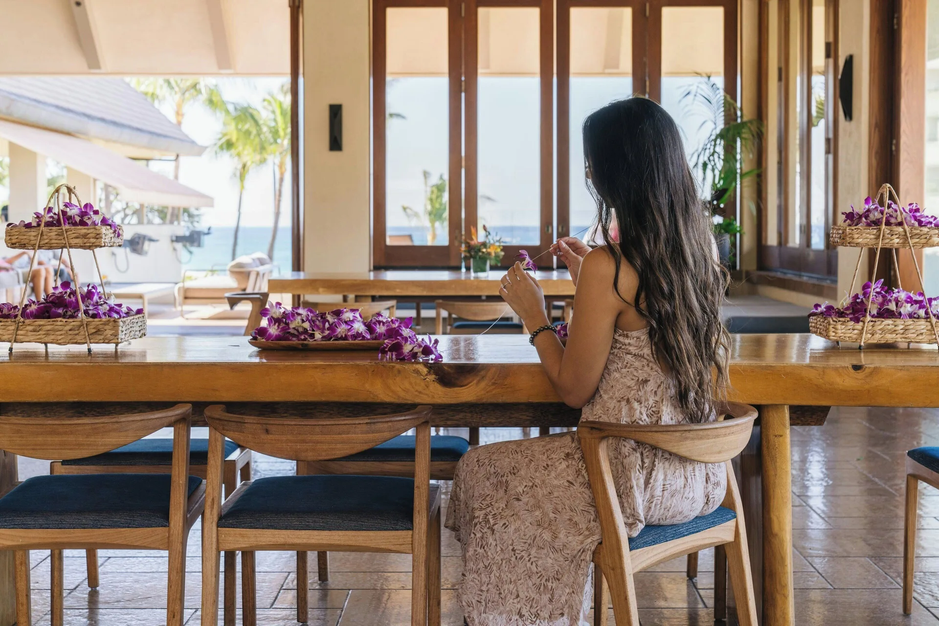Guest makes a flower lei at a long wood table at Sheraton Maui Resort & Spa.