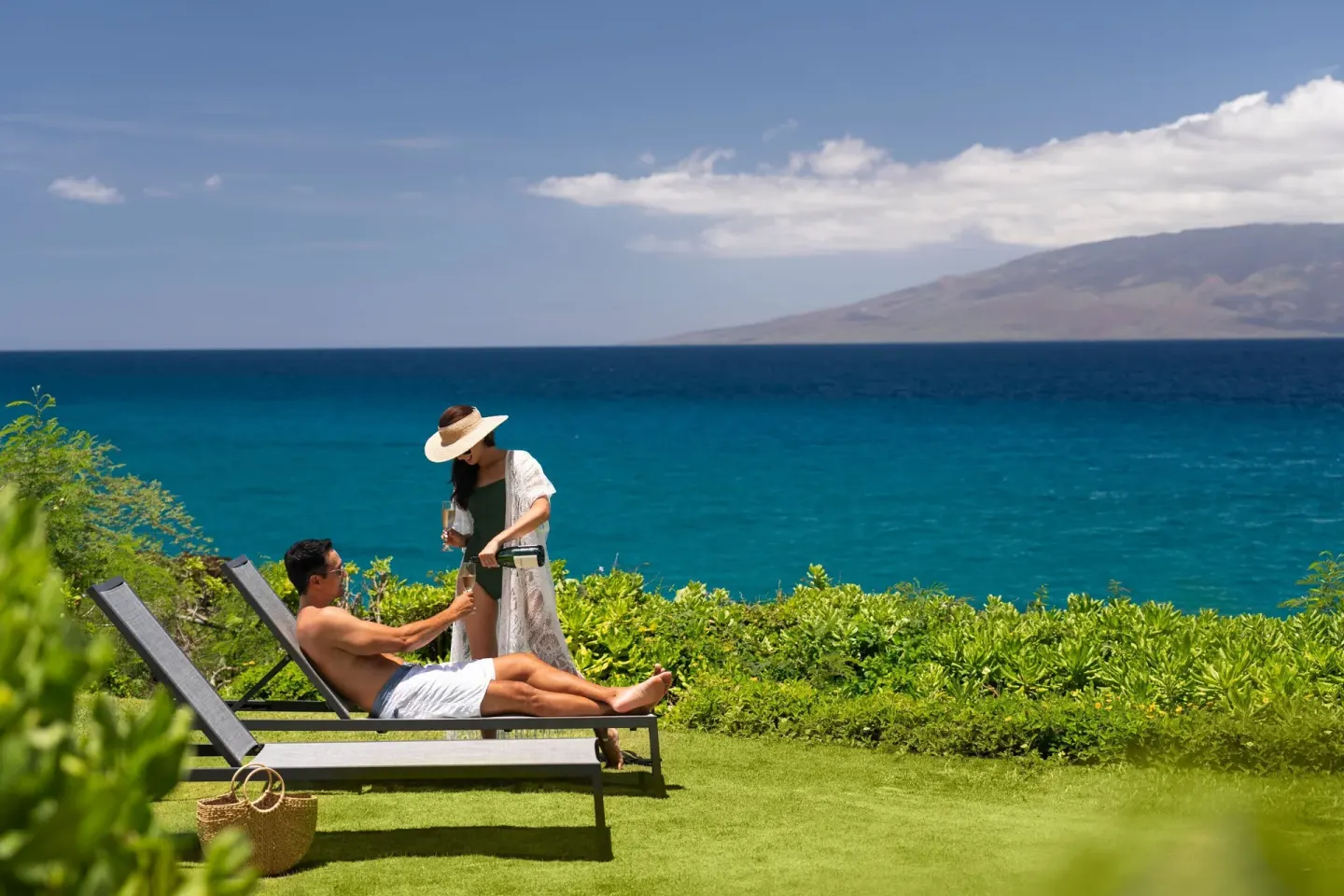 Couple relaxing on oceanfront lounge chairs at Sheraton Maui Resort & Spa.