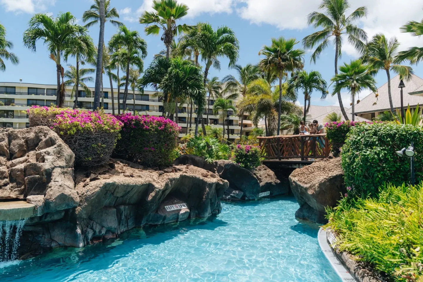 Pool channel, rock walls, bridge, palms, and resort buildings at Sheraton Maui Resort & Spa.