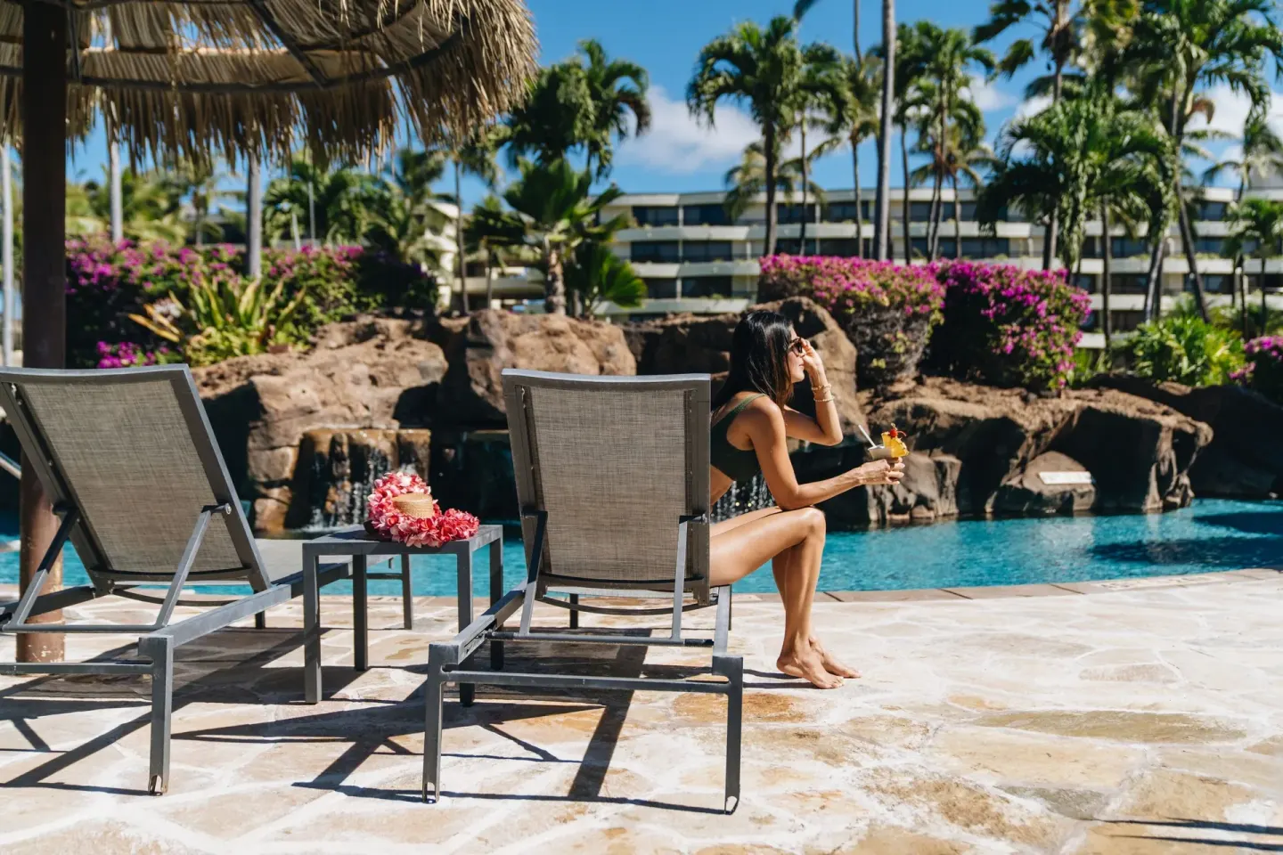 Guest relaxing on a lounge chair beside the pool at Sheraton Maui Resort & Spa.