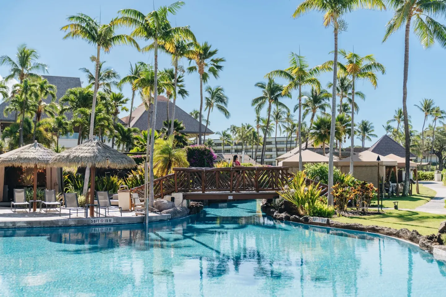 Resort pool with palms, bridge, cabanas, and thatched umbrellas at Sheraton Maui Resort & Spa.