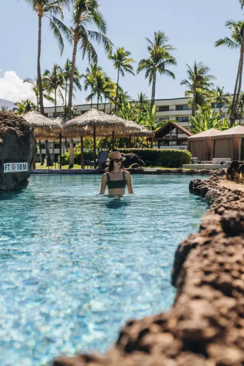 Guest wading in a rock-lined pool channel at Sheraton Maui Resort & Spa.