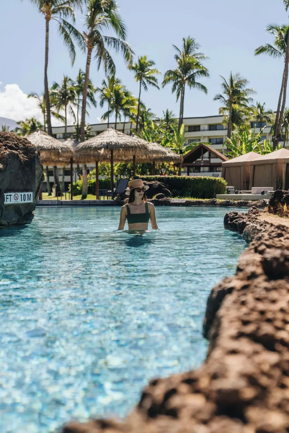 Guest wading in a rock-lined pool channel at Sheraton Maui Resort & Spa.