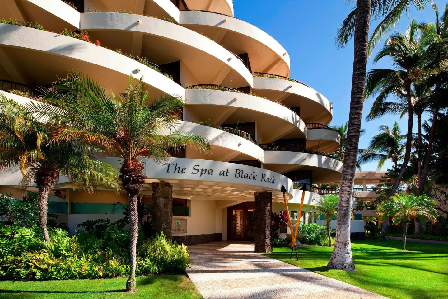 Spa entrance beneath curved balconies and palms at Sheraton Maui Resort & Spa.