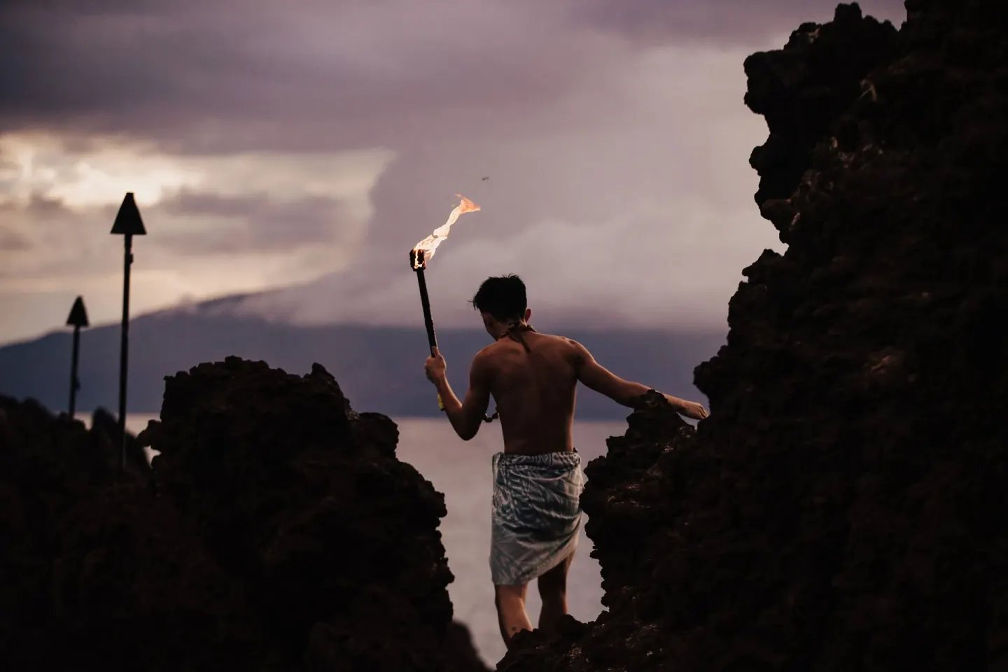 Torch bearer walking through black lava rocks at Sheraton Maui Resort & Spa.
