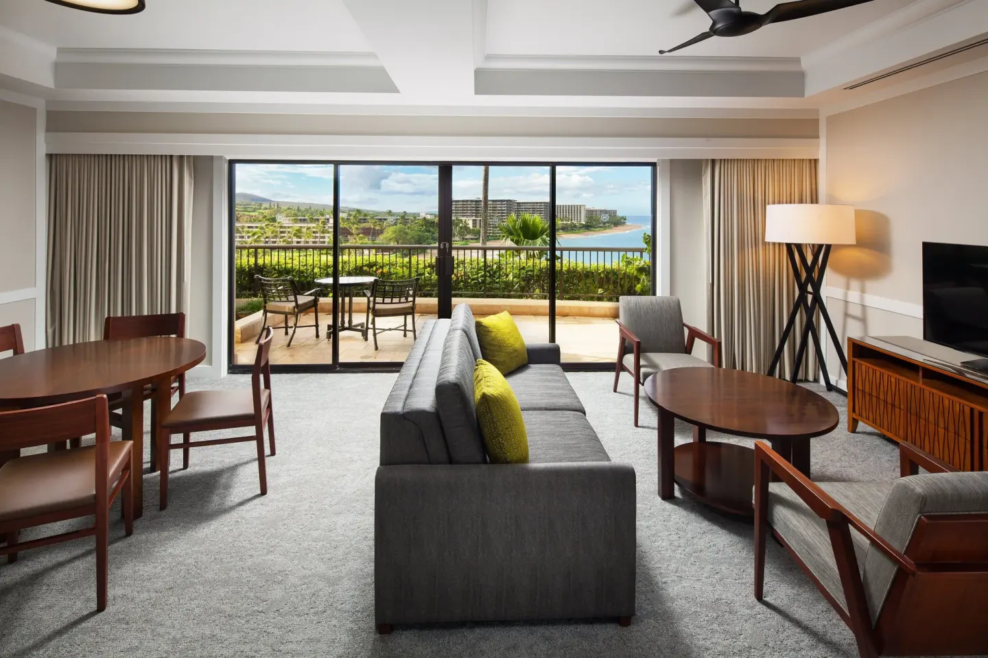 Oceanfront living room in a Deluxe Suite at Sheraton Maui Resort & Spa with sofa, dining table, and lanai.
