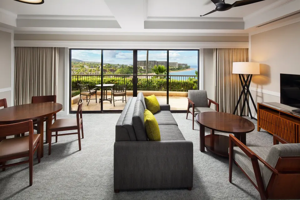 Deluxe Suite oceanfront living area with sofa, dining table and lanai at Sheraton Maui Resort & Spa.