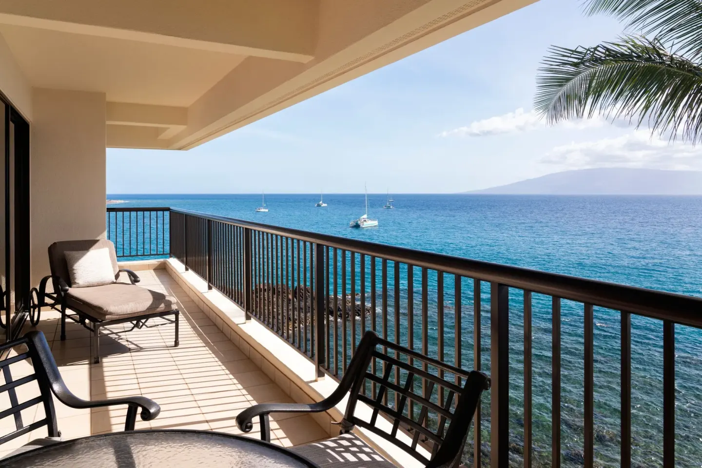 Oceanfront lanai seating at Sheraton Maui Resort & Spa with blue water and sailboats beyond.