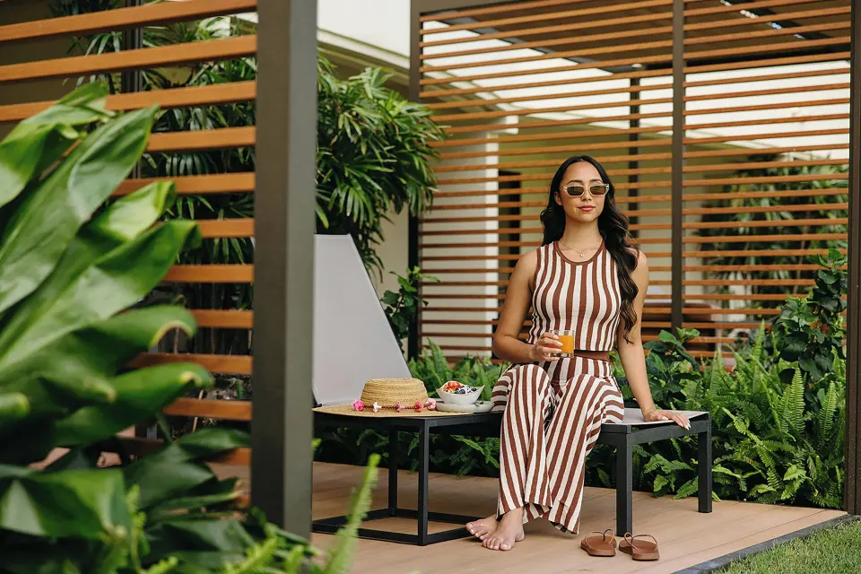 Guest seated with a drink on a Premium Lanai patio at Sheraton Maui Resort & Spa.