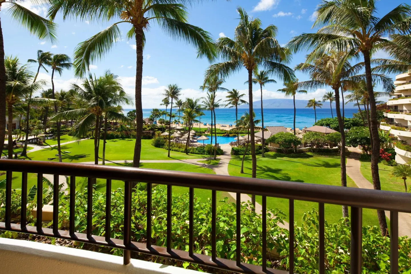Ocean view from a guest room balcony at Sheraton Maui Resort & Spa, with palms, lawns and pool below.