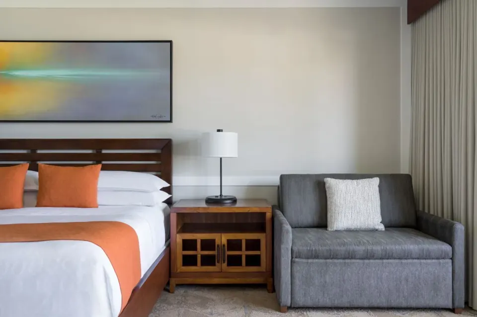 King bed and gray sofa in a Resort View room at Sheraton Maui Resort & Spa.