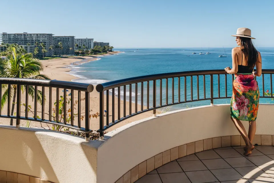 Guest on a suite balcony overlooking the beach at Sheraton Maui Resort & Spa.