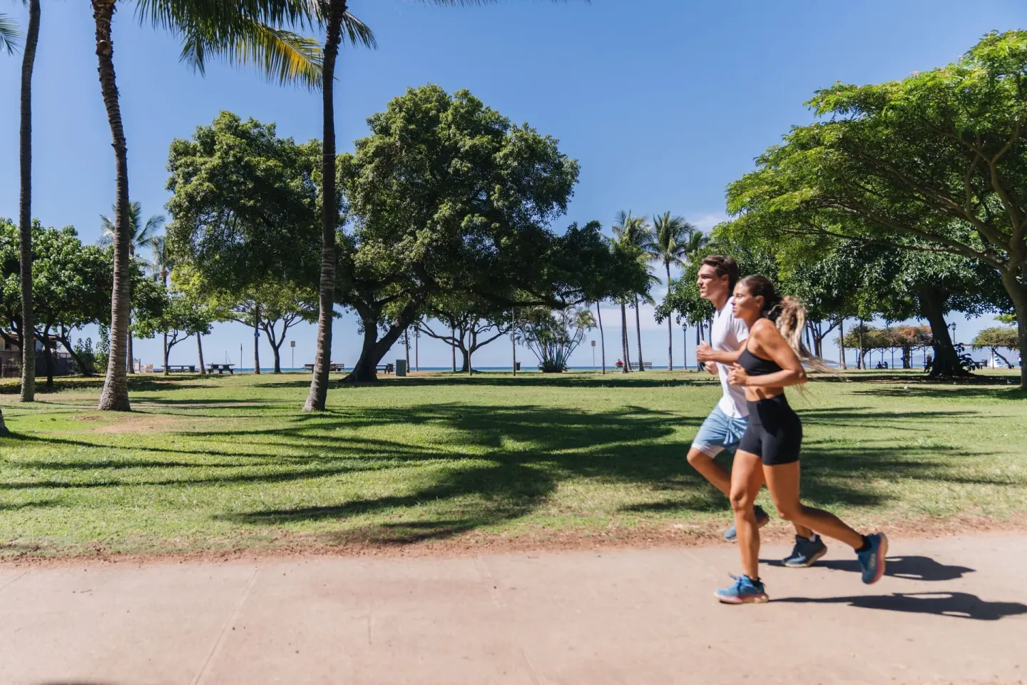 Two runners jog past palm trees near the beach at Sheraton Princess Kaiulani.