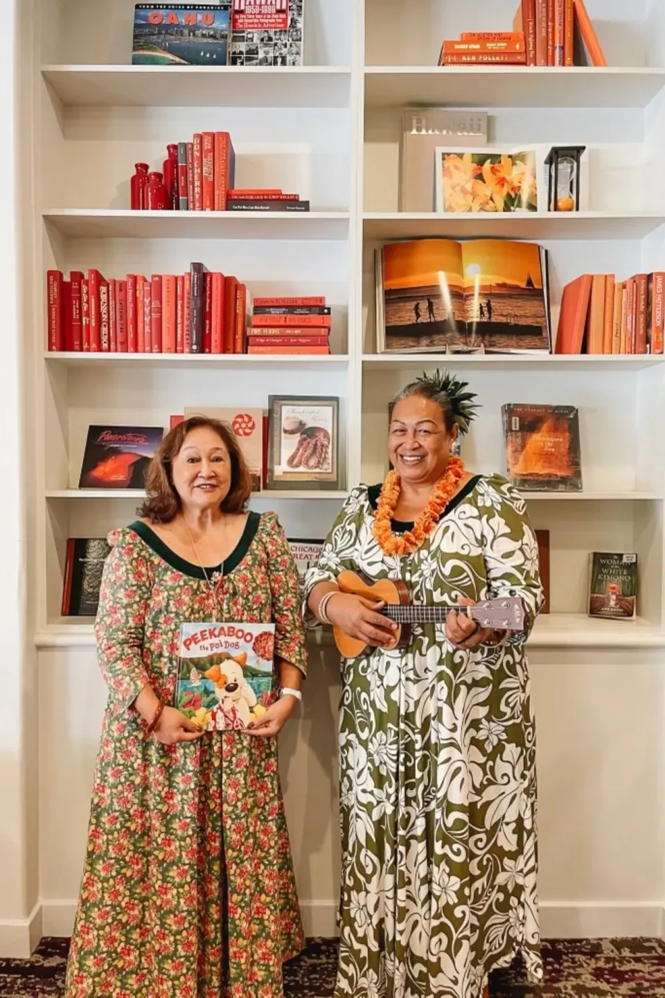 Two women pose with a ukulele and children’s book by shelves at Sheraton Princess Kaiulani.