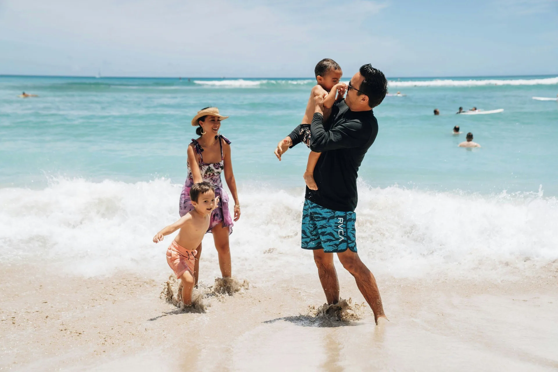 Family wades in the surf near Sheraton Princess Kaiulani.