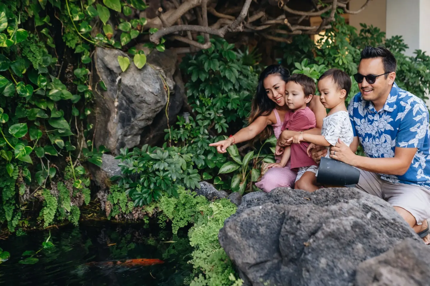 A family watches fish in a garden pond at Sheraton Princess Kaiulani.