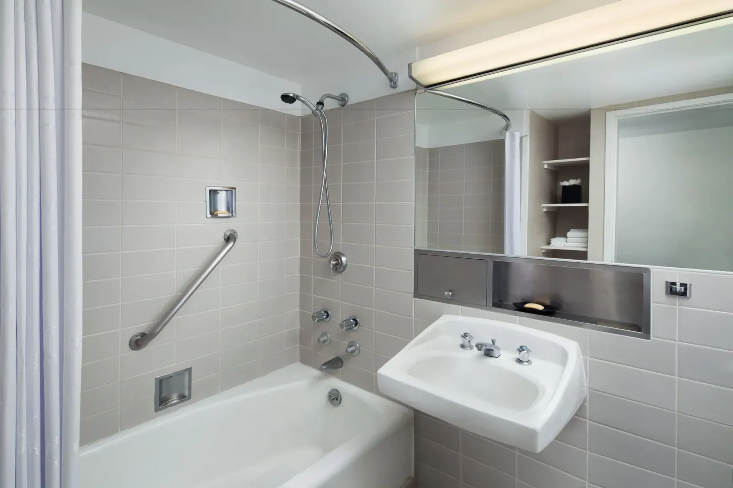 Bathroom with tub, shower curtain, sink, mirror, and grab bar at Sheraton Princess Kaiulani.