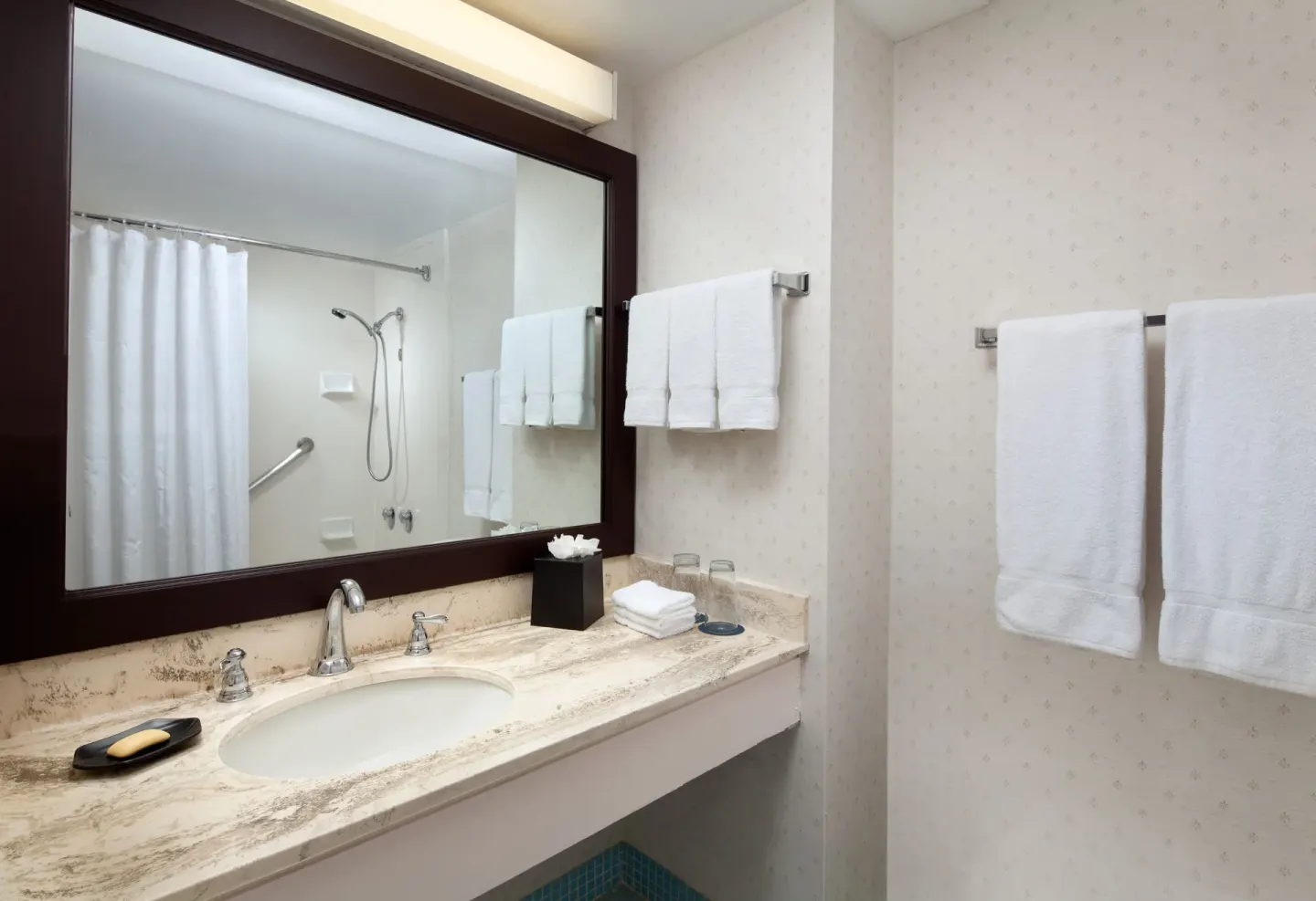 Bathroom vanity with large mirror, towels, and shower reflection at Sheraton Princess Kaiulani.