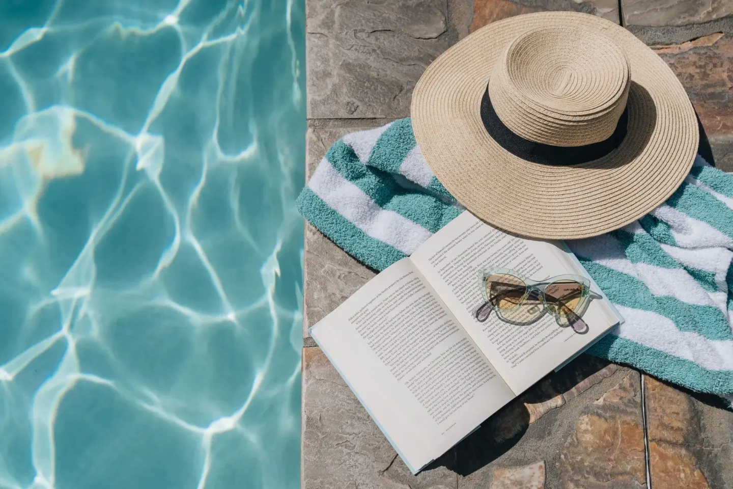 Poolside towel, hat, sunglasses, and open book beside the water at Sheraton Princess Kaiulani.