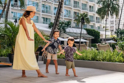 A woman and two children walk on a terrace at Sheraton Princess Kaiulani.