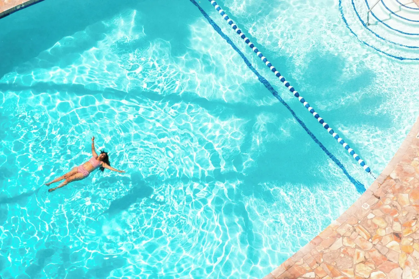 Swimmer floats in the bright blue pool at Sheraton Princess Kaiulani.