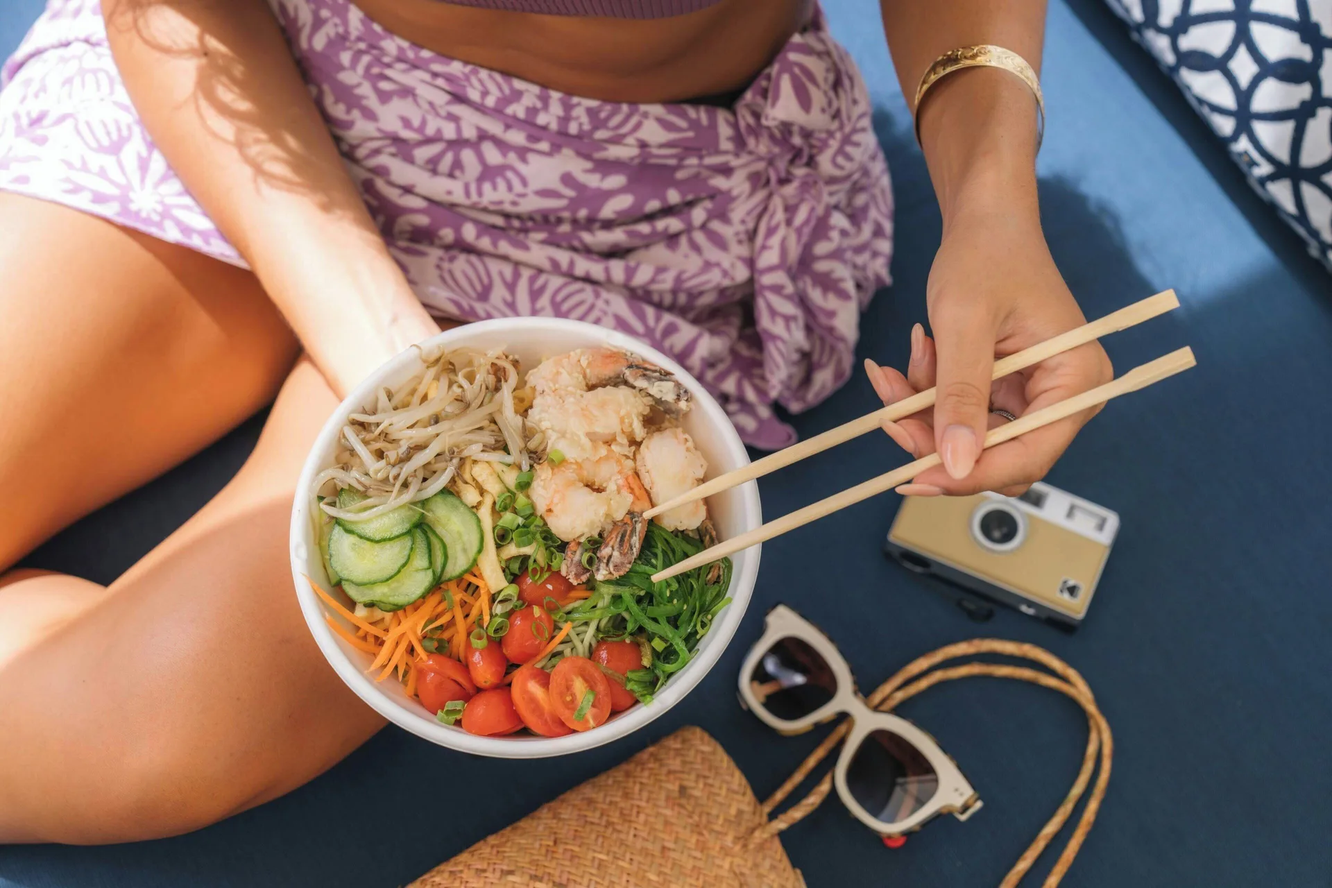 A guest holds a colorful bowl with chopsticks at Sheraton Princess Kaiulani.
