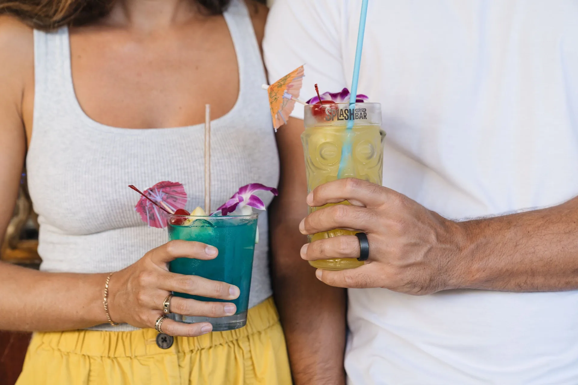 Two guests hold colorful tropical drinks with umbrellas at Sheraton Princess Kaiulani.