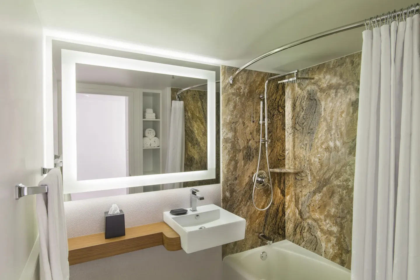 Kaiulani bathroom with illuminated mirror, sink, and tub shower at Sheraton Princess Kaiulani.