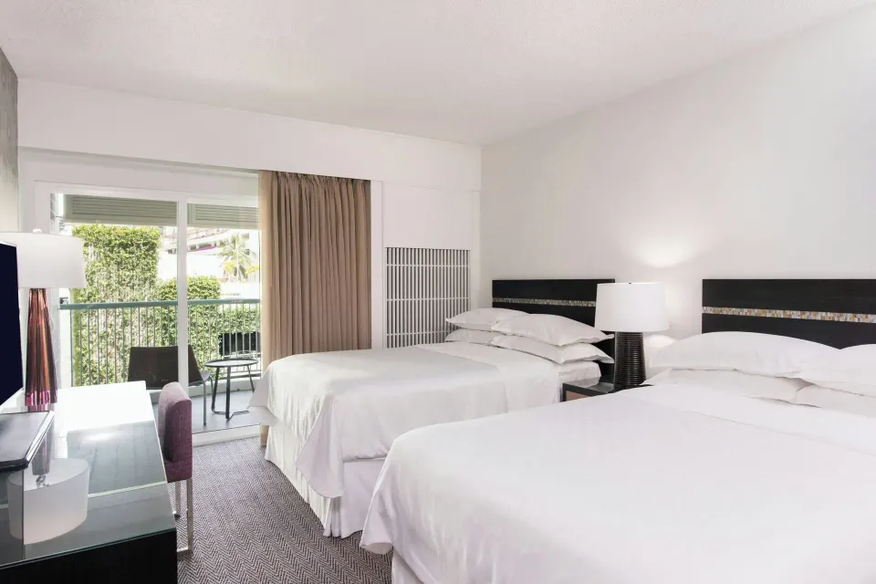 Kaiulani guest room with two beds, TV console, and balcony at Sheraton Princess Kaiulani.