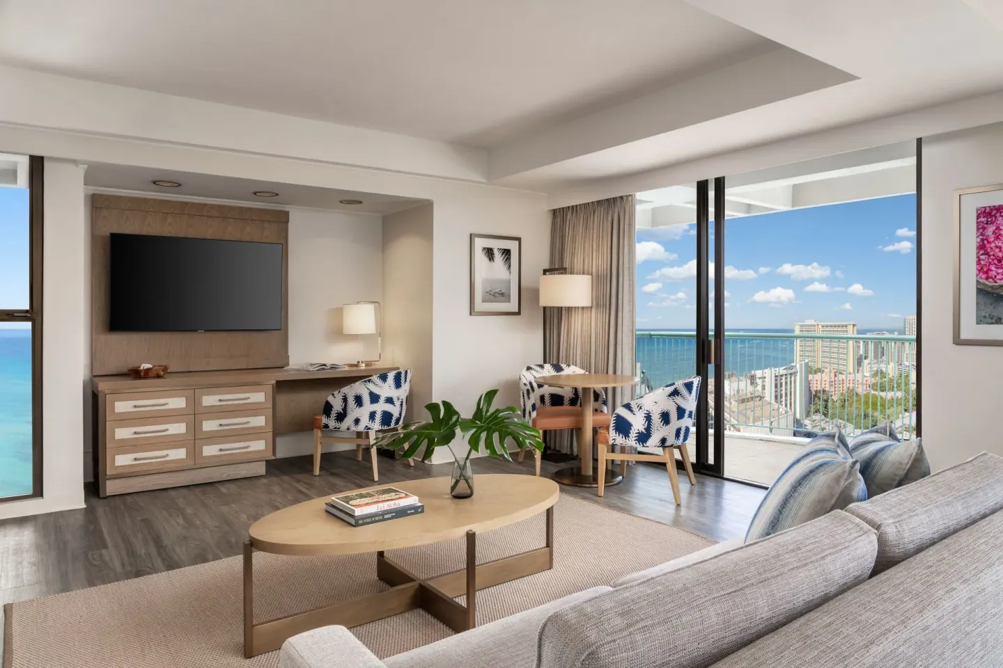 Renovated Corner Jr. Suite living area at Sheraton Princess Kaiulani with TV, desk, sofa, and balcony.