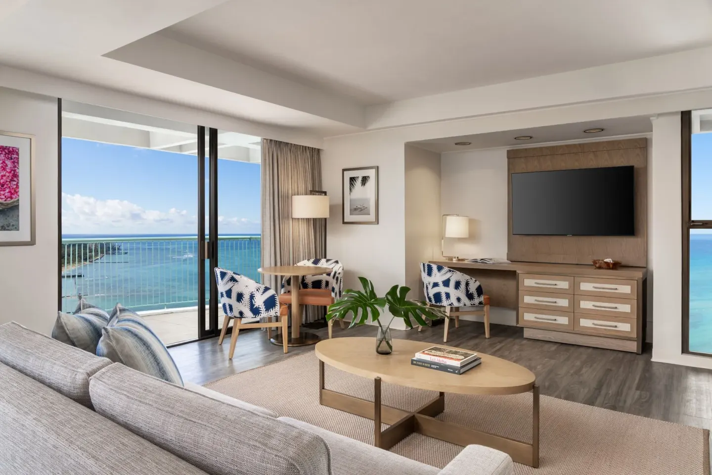 Renovated Corner Jr. Suite lounge at Sheraton Princess Kaiulani with sofa, table seating, TV, and ocean view.