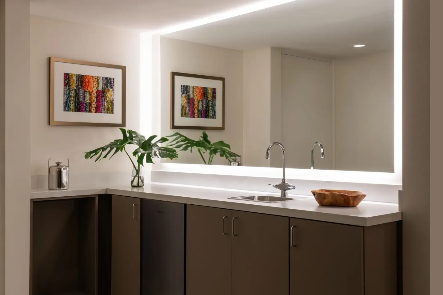 Renovated Corner Jr. Suite wet bar at Sheraton Princess Kaiulani with sink, cabinets, mirror, and artwork.